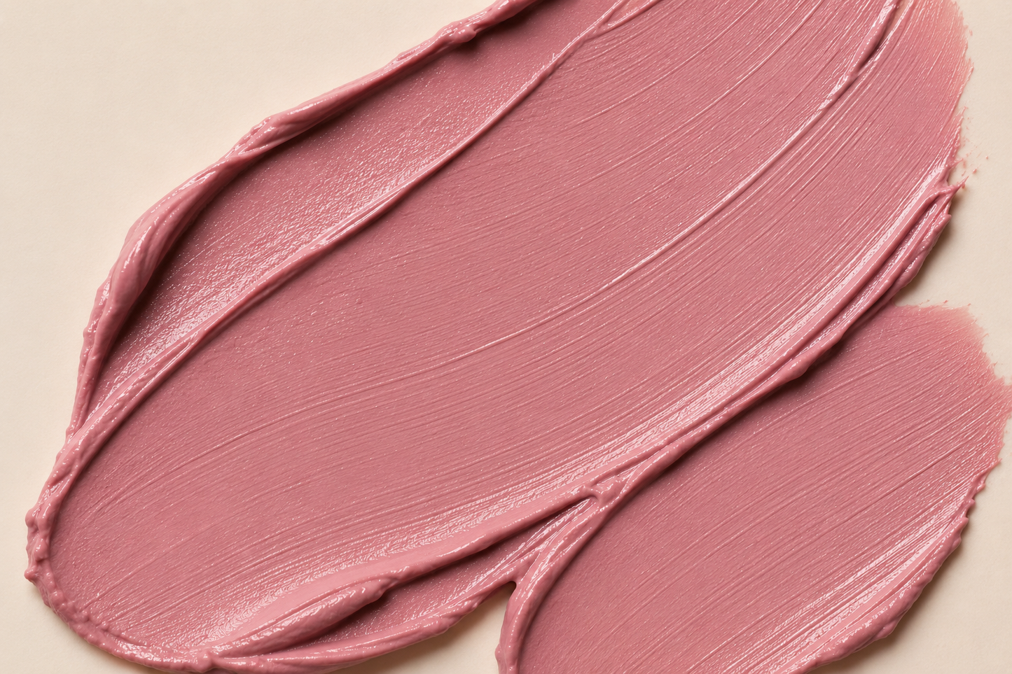 A close-up of a dusty rose pink cosmetic cream swatch, showing the thick, creamy texture and smooth swipe strokes on a light beige background.